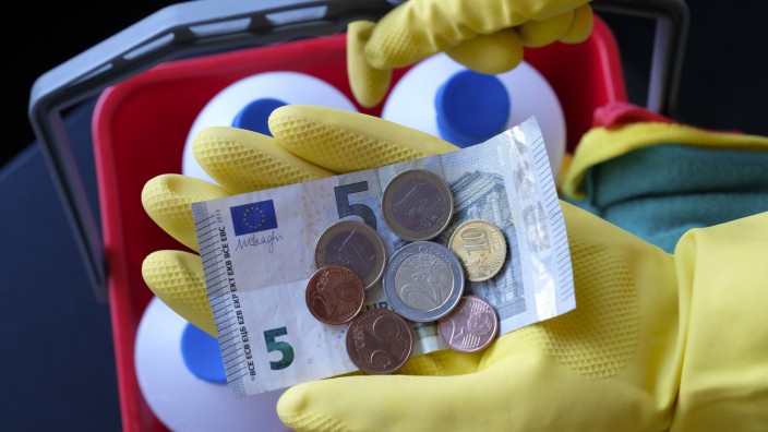 Eine Reinigungskraft haelt 9 19 Euro in ihrer Hand Der gesetzliche Mindestlohn wird zum 1 Januar 2
