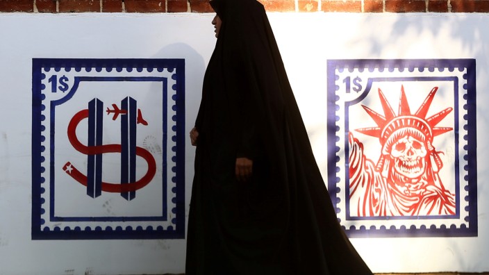 A woman walks past an Anti US mural on the former US embassy's wall in Tehran