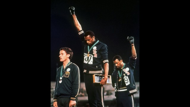 SZ-Serie: Olympisches Erbe: Damals bei Olympia verboten: Die amerikanischen Leichtathleten Tommie Smith (Mitte) und John Carlos (rechts) recken bei den Spielen 1968 in Mexiko-Stadt die Faust in die Luft, um gegen Rassismus zu protestieren.