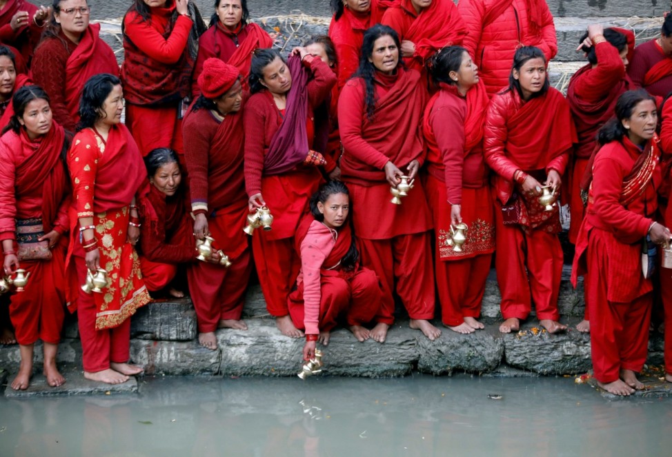 Devotees holding water pots wait to fill water from the Bagmati River, which is considered by them to be holy, during the Swasthani Brata Katha festival in Kathmandu