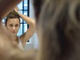 Woman doing hair in bathroom mirror PUBLICATIONxINxGERxSUIxAUTxONLY Copyright: FrédéricxCirou B15688124
