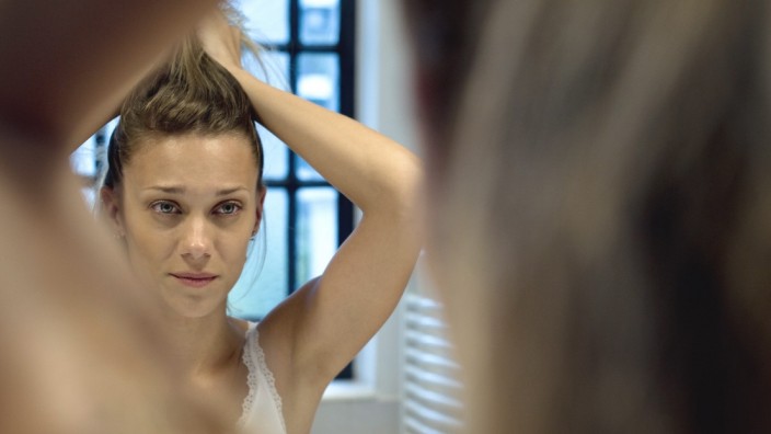 Woman doing hair in bathroom mirror PUBLICATIONxINxGERxSUIxAUTxONLY Copyright: FrédéricxCirou B15688124