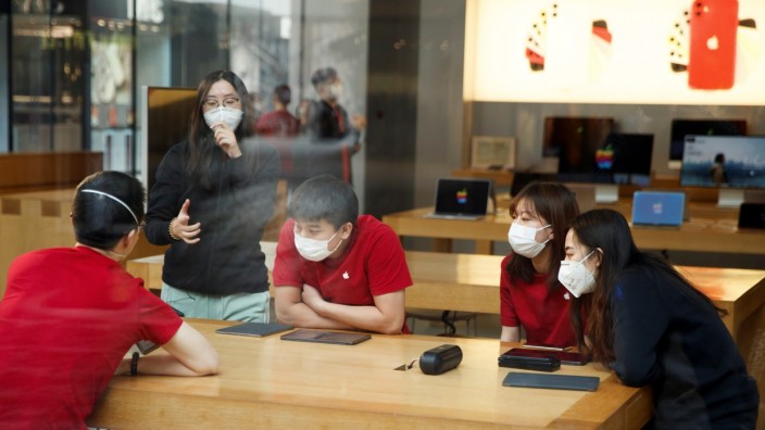 People wear face masks as they listen to a presentation in an Apple Store in the Sanlitun shopping district in Beijing