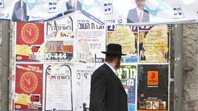 Israel vor der Wahl: Ein ultraorthodoxer Jude geht an Wahlplakaten vorüber. "Wäre das Gesamtbild klarer", schreibt Assaf Gavron, "wüssten wir, dass wir eh nichts ändern".