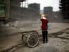 Ou Mei, a 45-year-old female migrant construction worker, shields her face from dust during a shift at a residential construction site in Shanghai