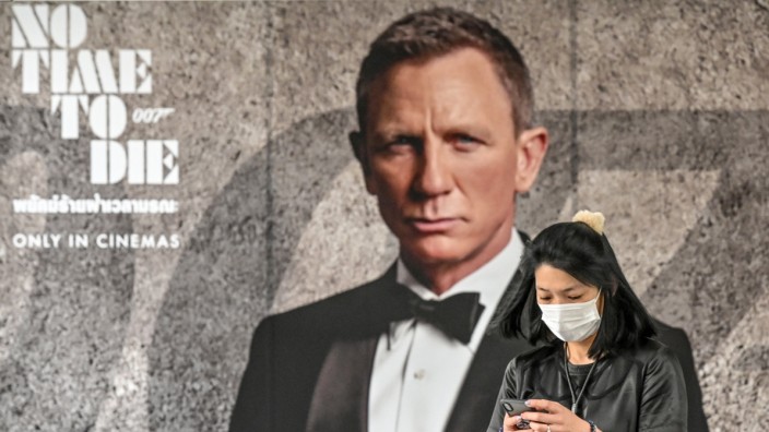 25. James-Bond-Film: Eine Frau mit Gesichtsmaske vor einem Poster des neuen James Bond Films "Keine Zeit zu sterben" in Bangkok.