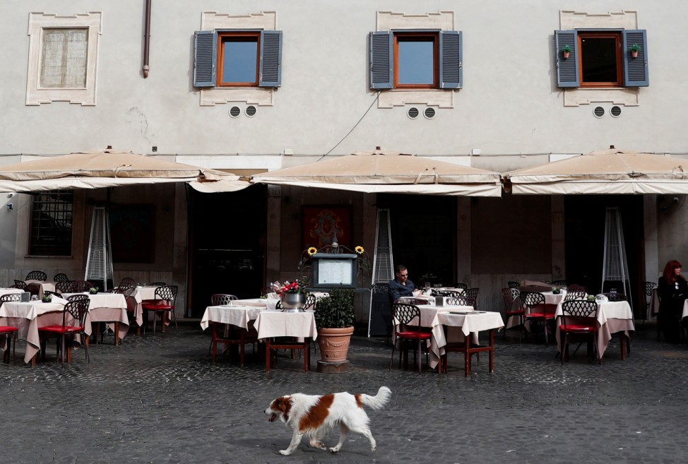 A dog passes in front of an almost empty restaurant in Trastevere area, after a decree orders for the whole of Italy to be on lockdown in an unprecedented clampdown aimed at beating the coronavirus,in Rome
