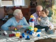 Great grandparents and baby girl playing together with plastic building bricks at home model release