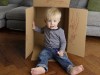 Smiling toddler sitting in a cardboard box at home model released Symbolfoto property released PUBLI