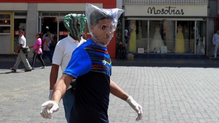 Men cover their faces with plastic bags in response to the spreading coronavirus (COVID-19) in Caracas