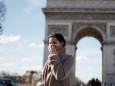 A woman wearing a protective mask, walks near Arc de Triomphe as France grapples with an outbreak of coronavirus (COVID-19) disease, in Paris