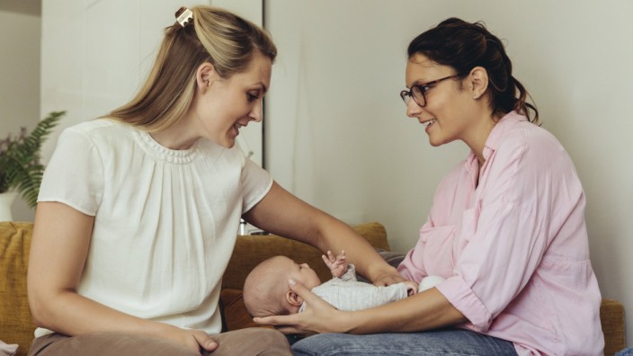 Midwife and mother giving newborn baby a belly massage to help with digestion model released Symbolf