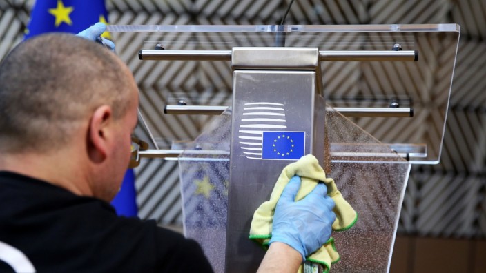 A man disinfects a desk before a news conference of European Council President Charles Michel in Brussels