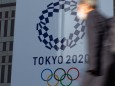 A man walks past a large display promoting the Tokyo 2020 Olympics in Tokyo, Japan on March 25, 2020, a day after the T; Tokio Olympia