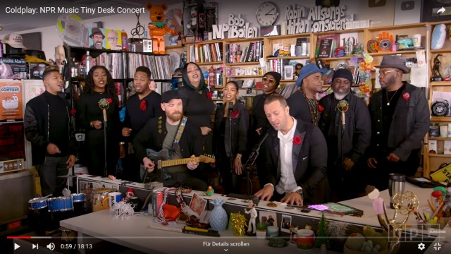 Tiny Desk Concerts: Chris Martin mit Coldplay-Komplizen und Gospel-Chor während ihres Auftritts hinter dem Schreibtisch.