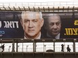 Israelis walk on a bridge beneath election campaign posters for Benny Gantz s Blue and White Party, on Monday, February
