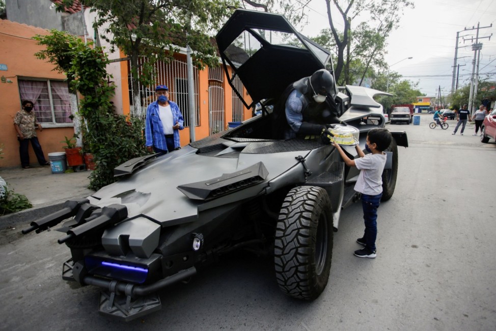 Mexican lawyer Candelario Maldonado, dressed up as the fictional character Batman, gives a birthday cake to a child wearing face mask in front of his home, during the global outbreak of the coronavirus disease (COVID-19), in Monterrey