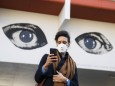Corona-Krise: Frau mit Mundschutz schaut auf ihr Handy