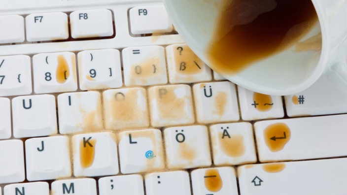 Kaffeetasse ausgeschuettet auf die Tastatur eines Computers Cup of coffee spilled on a computer keyboard