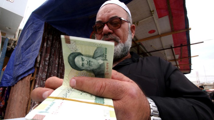 FILE PHOTO: A man buys Iranian rials from a seller of Iranian currency, before the start of the U.S. sanctions on Tehran, in Basra