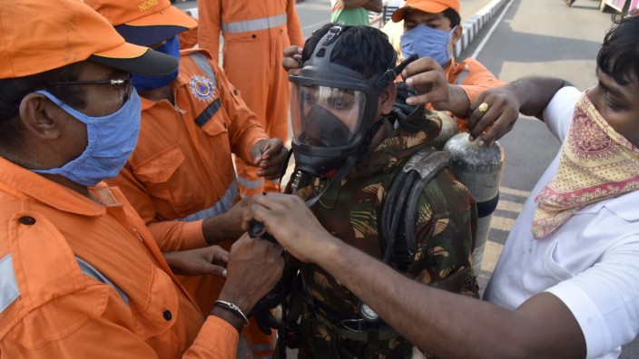 Indien: Ein Mitarbeiter der Katastrophenschutzbehörde streift eine Maske über, bevor er das Gelände betritt, wo der Chemieunfall passierte.