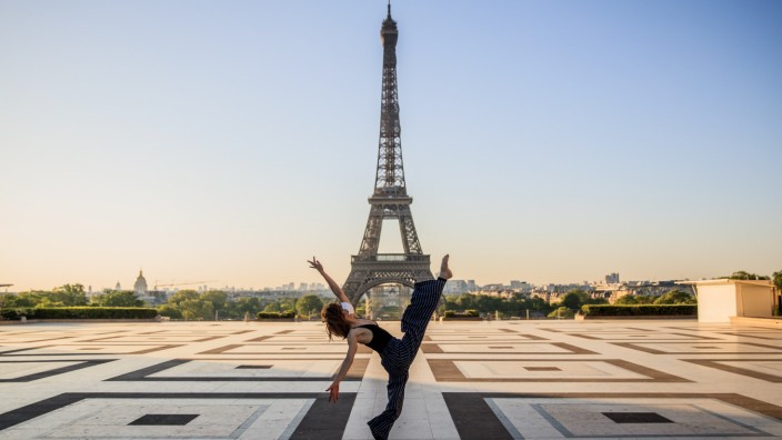 Coronavirus: Eine Frau tanzt mit Mundschutz in Sichtweite des Eiffelturms.