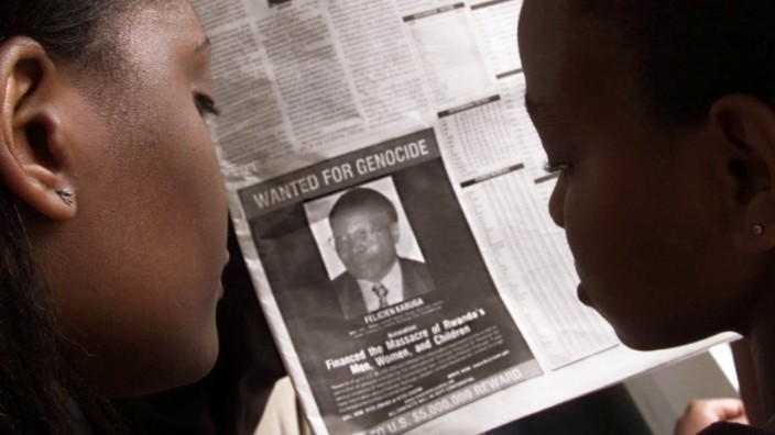 FILE PHOTO: READERS LOOK AT A PICTURE OF A RWANDAN WANTED FOR ALLEGED ROLE IN  RWANDA'S 1994 GENOCIDE.
