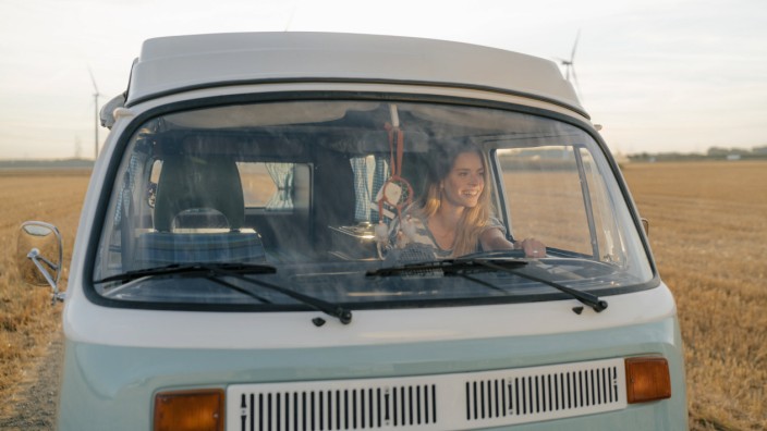 Smiling young woman driving camper van in rural landscape model released Symbolfoto PUBLICATIONxINxG