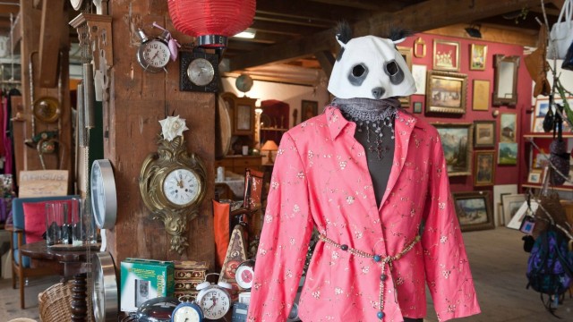 Trödlerin: Die Schaufensterpuppe trägt Kreuzschmuck unter dem Halstuch und eine Pandamaske über dem Kopf.