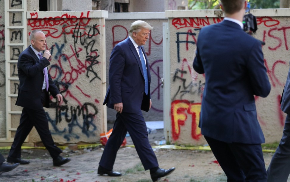 U.S. President Trump walks past a building defaced with graffiti by protestors in Washington