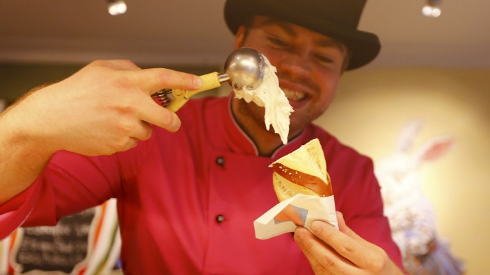 Ice-cream maker Matthias Muenz scoops white sausage flavoured ice-cream on a pretzel in his shop in Munich