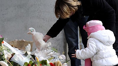 Belgien: Amoklauf im Kindergarten: Eine Mutter legt mit ihrem Kind einen Stoffhasen vor dem Kindergarten "Märchenland" in Dendermonde nieder. Nach wie vor sind die Eltern der Opfer über das Motiv des Täters im Unklaren.
