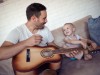 Father teaching his son how to play guitar.; Kinder Musik