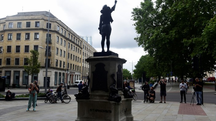 People take pictures of the sculpture of a Black Lives Matter protester standing on the empty plinth previously occupied by the statue of slave trader Edward Colston, in Bristol
