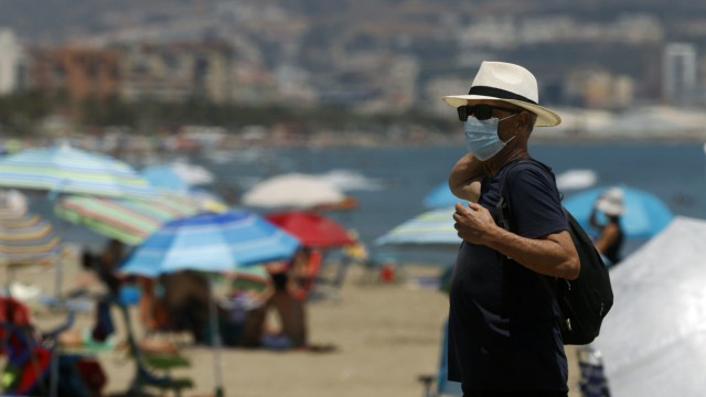 Ein Urlauber mit Mundschutz steht an einem Strand in Malaga in Spanien.