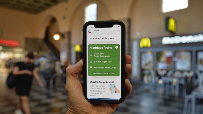 Hand hält Smartphone mit Corona Warn-APP im Bahnhof, Corona-Krise, Stuttgart, Baden-Württemberg, Deutschland Coronaviru