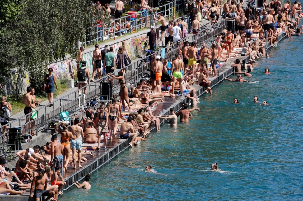 People enjoy hot summer weather on the banks of the Limmat river in Zurich
