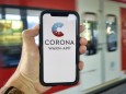 Hand hält Smartphone mit Corona Warn-APP am Bahnsteig, Corona-Krise, Stuttgart, Baden-Württemberg, Deutschland Coronavi