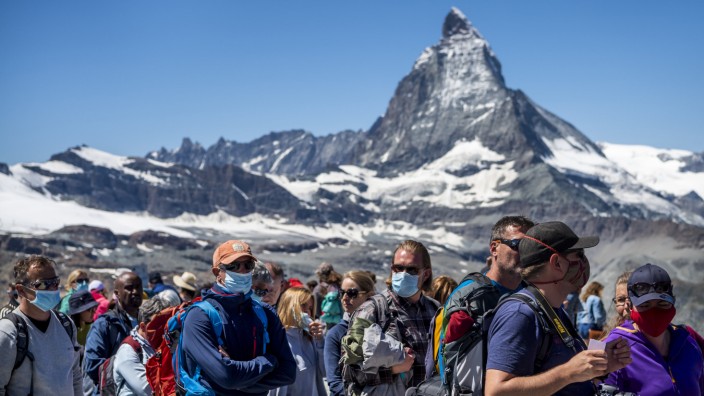 Touristen mit Mundschutz warten vor dem Matterhorn auf den Zug der Gornergratbahn.