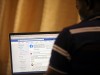 FILE PHOTO: Man opens the Facebook page on his computer to fact check coronavirus disease (COVID-19) information, in Abuja