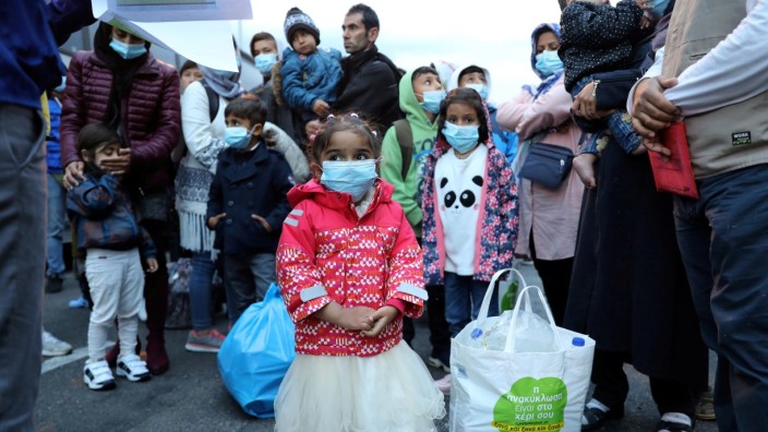 FILE PHOTO: Migrants from the Moria camp in Lesbos wait to board busses at Piraeus port in Athens following the coronavirus disease (COVID-19) outbreak