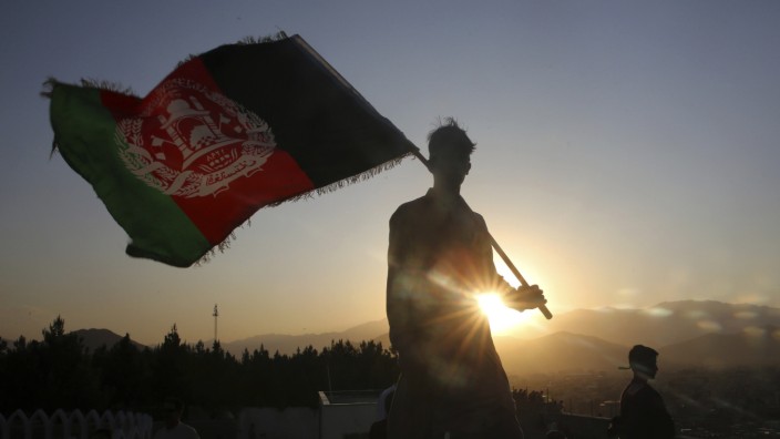 Afghanistan: Ein Mann in Kabul schwenkt die afghanische Flagge. In dem Land sollen nach 19 Jahren Krieg Friedensgespräche zwischen Regierung und Taliban beginnen.