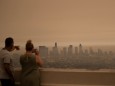 People watch as tick smoke from the Bobcat fire moves through Los Angeles