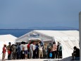 Refugees and migrants from the destroyed Moria camp gather outside a UNHCR tent at a new temporary camp on the island of Lesbos