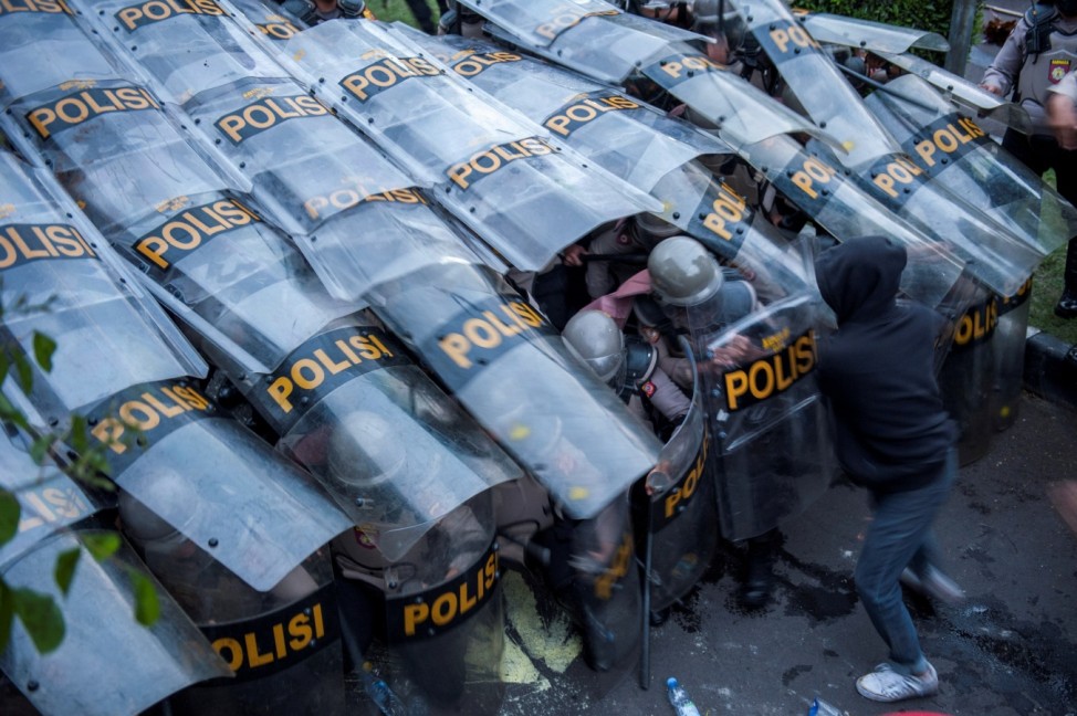 A demonstrator clashes with a barricade of police officers during a protest against the government's proposed labour reforms in a controversial 'jobs creation' bill outside the Regional Parliament building in Bandung