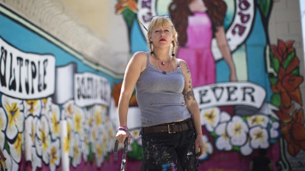 Street artist Lydia Emily Archibald, who was diagnosed with Multiple Sclerosis in 2012, poses by her mural aimed at raising awareness about the disease in Los Angeles, California