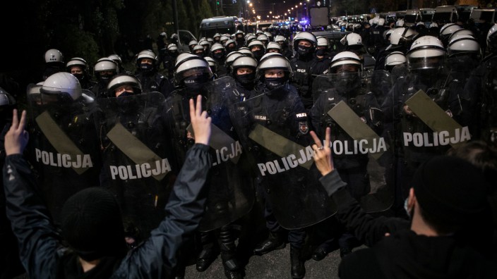 Demonstrierende stehen vor einer Wand aus Polizisten mit Schilden.