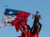 A demonstrator flutters a Chilean national flag from the top of the General Baquedano monument