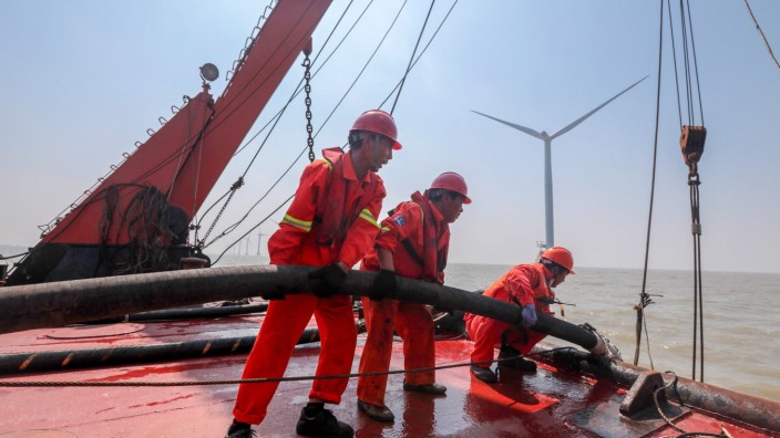 ZHOUSHAN, CHINA - SEPTEMBER 03: Employees of State Grid Corporation of China install a wind turbine at an offshore wind