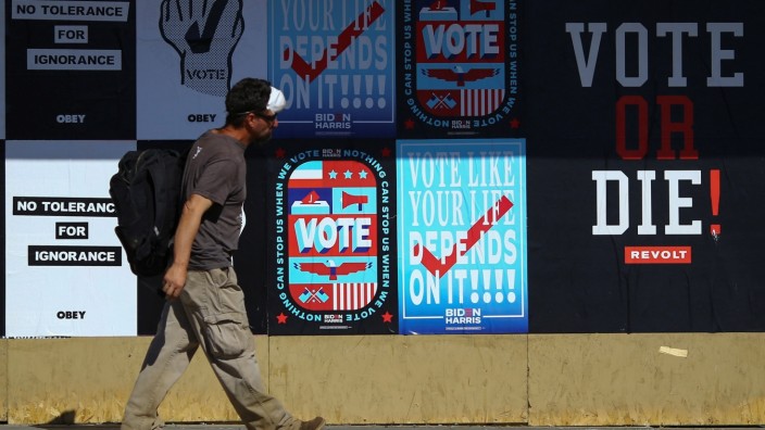 A man walks past voting signs in Phoenix, Arizona